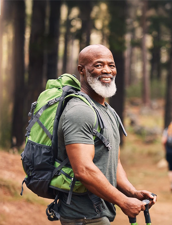 smiling senior man backpacking through the woods