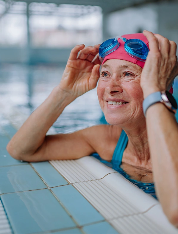happy senior woman in the pool adjusting her goggles