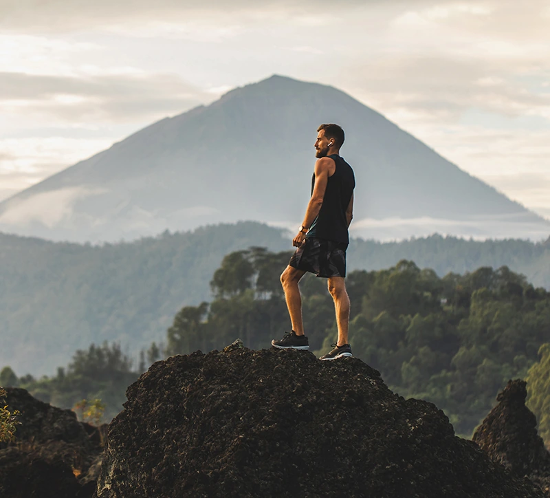 young athletic man hiking and looking out over mountainous landscape